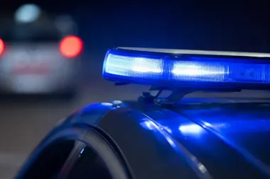 Nocny zbliżenie na niebieski sygnał świetlny na dachu policyjnego radiowozu, w tle rozmyty inny samochód.